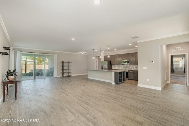 unfurnished living room with visible vents, a healthy amount of sunlight, and crown molding