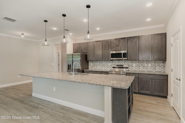 kitchen featuring stainless steel appliances, tasteful backsplash, dark brown cabinets, and a kitchen island with sink