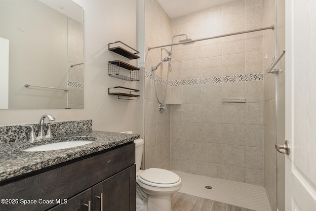 bathroom with vanity, toilet, and a tile shower