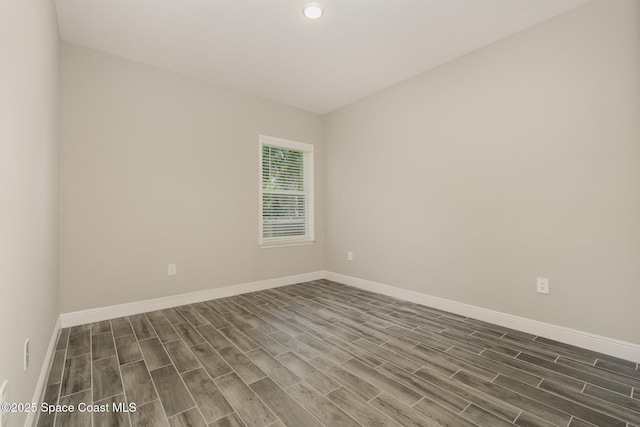 empty room with baseboards and dark wood-style floors