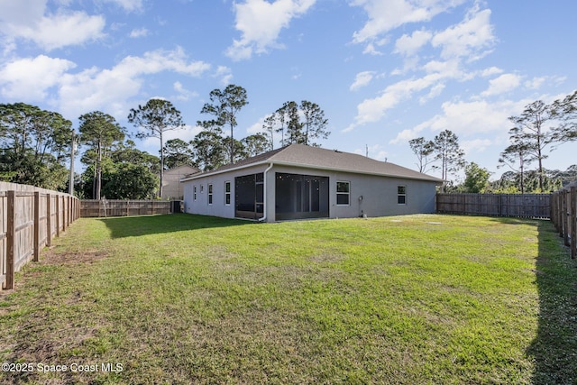 back of house featuring a yard, a fenced backyard, a sunroom, and stucco siding