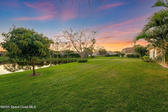 yard at dusk featuring a water view