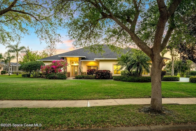 view of front of property with a lawn, roof with shingles, and stucco siding