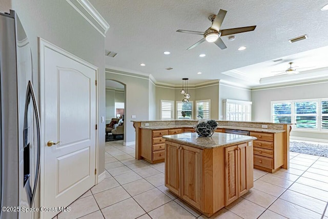 kitchen with visible vents, ornamental molding, ceiling fan, a large island, and stainless steel fridge