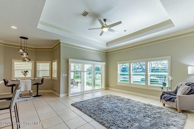 interior space featuring light tile patterned floors, a tray ceiling, a ceiling fan, and crown molding