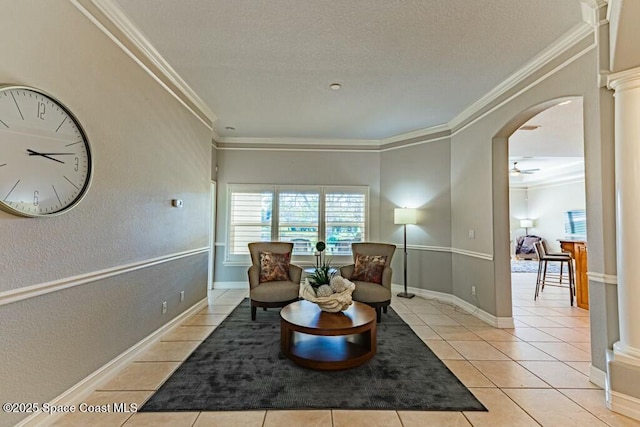 sitting room featuring light tile patterned flooring, crown molding, and ornate columns