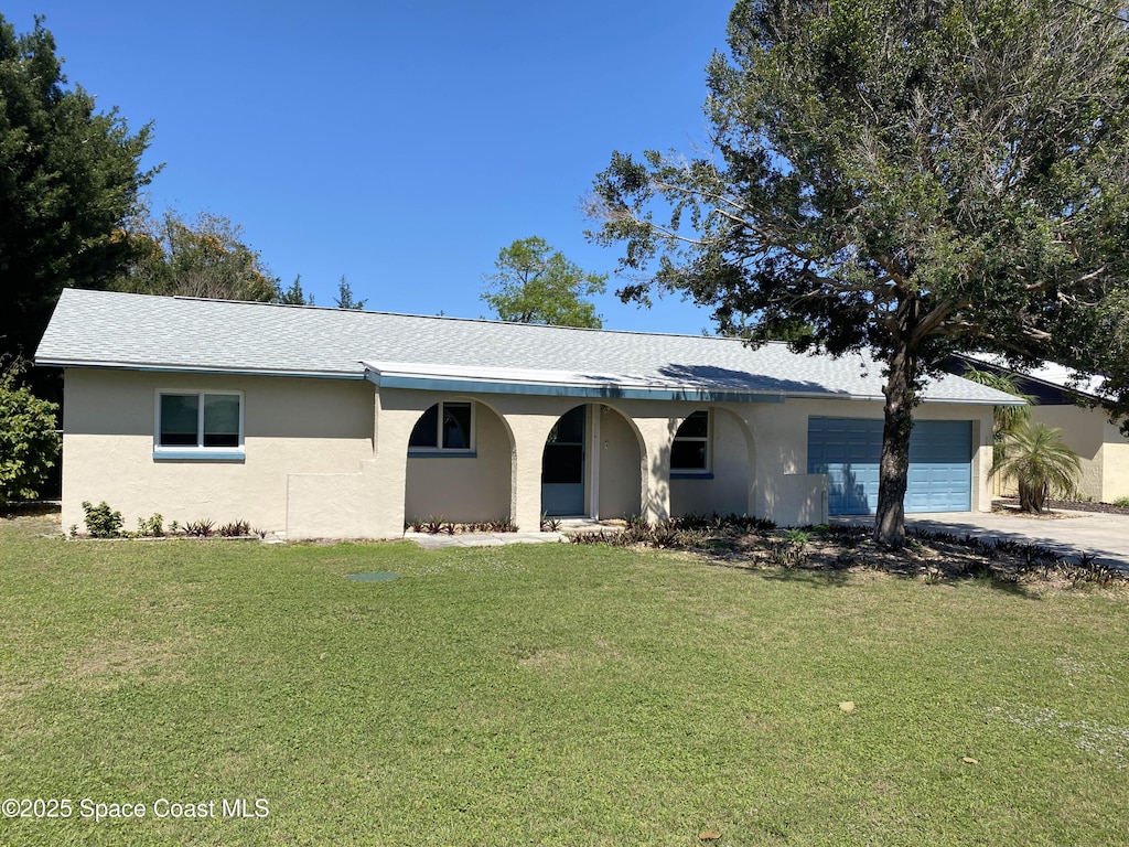 single story home with a porch, a front yard, stucco siding, a garage, and driveway