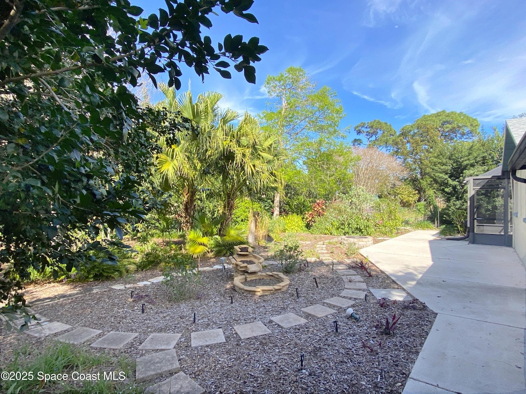 view of yard with a patio, a fire pit, and a lanai