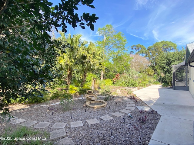 view of yard with a patio, a fire pit, and a lanai