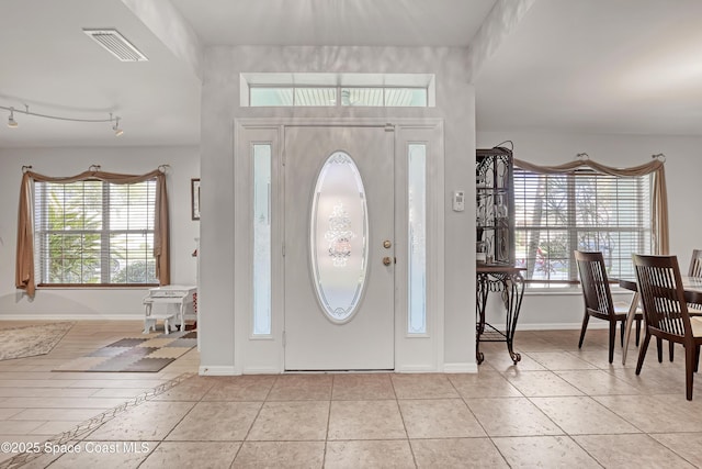 foyer with track lighting, light tile patterned floors, baseboards, and visible vents