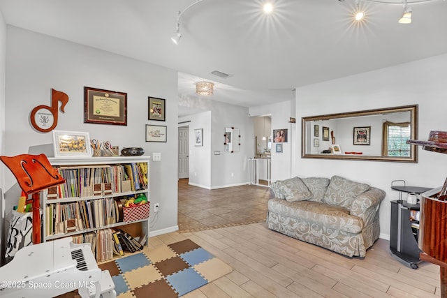 living room with visible vents, baseboards, wood finished floors, and track lighting