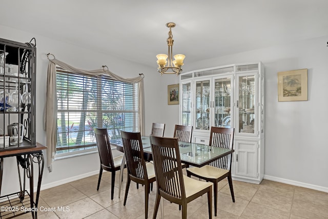 dining room featuring a notable chandelier, baseboards, and light tile patterned floors