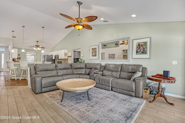 living room with visible vents, high vaulted ceiling, a ceiling fan, light wood finished floors, and baseboards