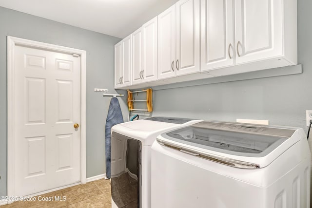 washroom with cabinet space, light tile patterned floors, and separate washer and dryer