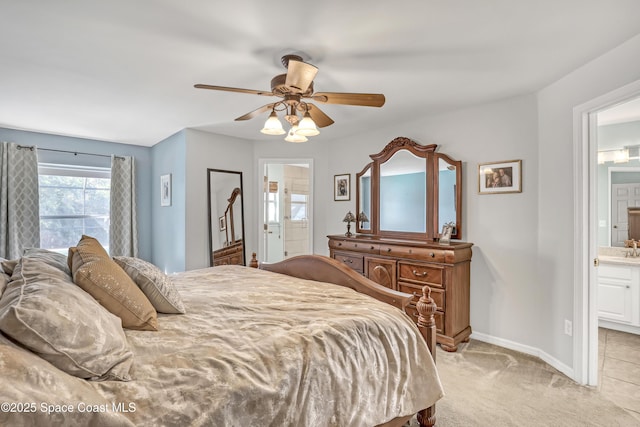 bedroom featuring light carpet, a ceiling fan, ensuite bathroom, and baseboards