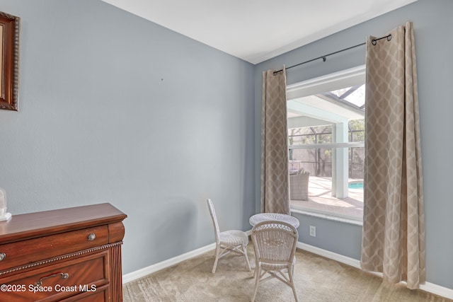 living area featuring light carpet and baseboards