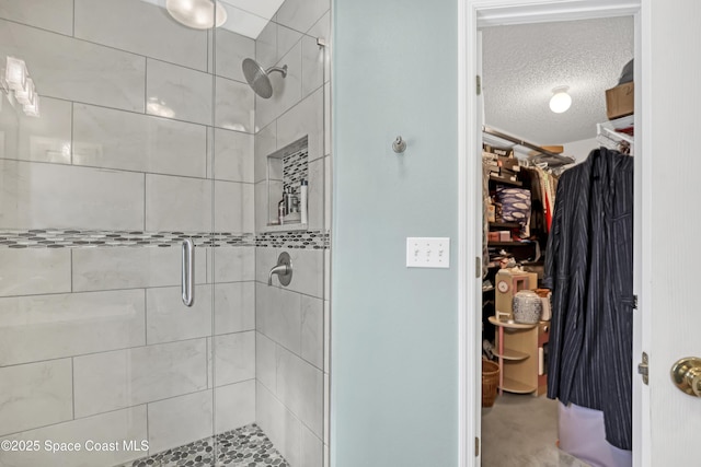 full bathroom with a spacious closet, a stall shower, and a textured ceiling