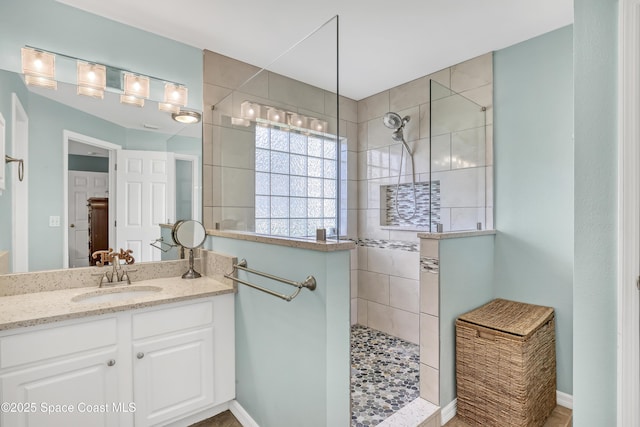 full bath with baseboards, vanity, and walk in shower