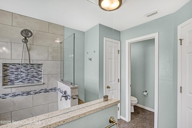 bathroom featuring visible vents, baseboards, tile patterned flooring, walk in shower, and toilet