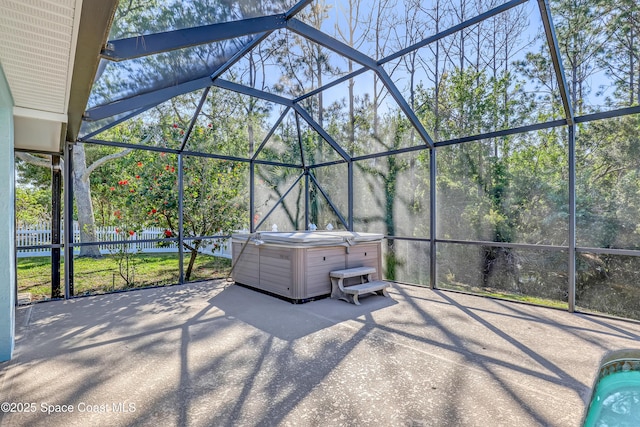 view of patio with glass enclosure, a hot tub, and fence