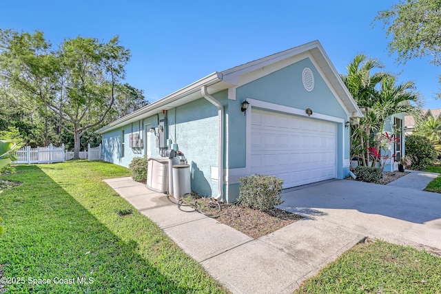 view of home's exterior with fence, concrete driveway, stucco siding, a yard, and an attached garage