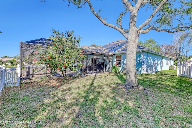 rear view of property featuring a yard, fence, and stucco siding