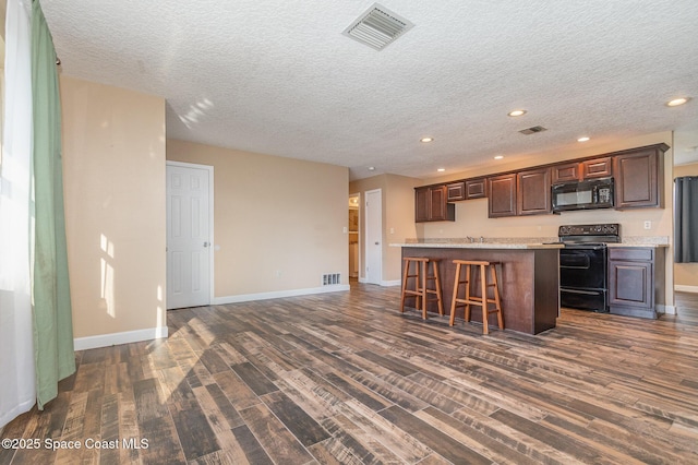 kitchen with visible vents, a center island, dark wood-type flooring, light countertops, and black appliances