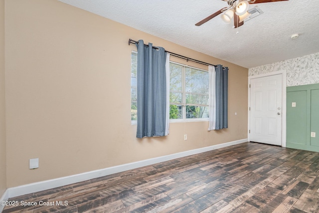 empty room with baseboards, dark wood-type flooring, ceiling fan, and a textured ceiling