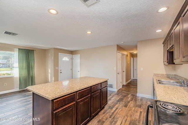 kitchen featuring black electric range oven, visible vents, dark wood-style flooring, and a sink