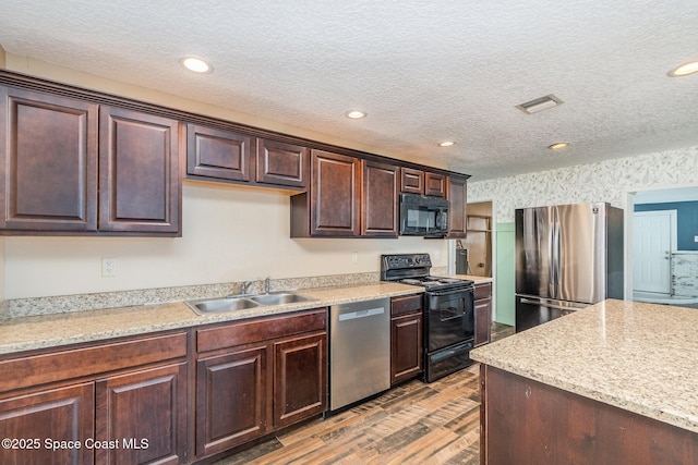 kitchen with visible vents, light countertops, wood finished floors, black appliances, and a sink