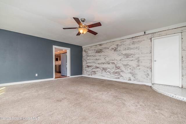 carpeted spare room featuring baseboards and a ceiling fan