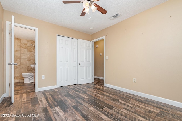 unfurnished bedroom featuring visible vents, baseboards, a closet, dark wood-style floors, and a textured ceiling