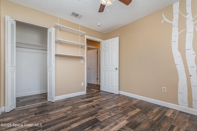 unfurnished bedroom with visible vents, baseboards, a closet, a textured ceiling, and dark wood-style flooring