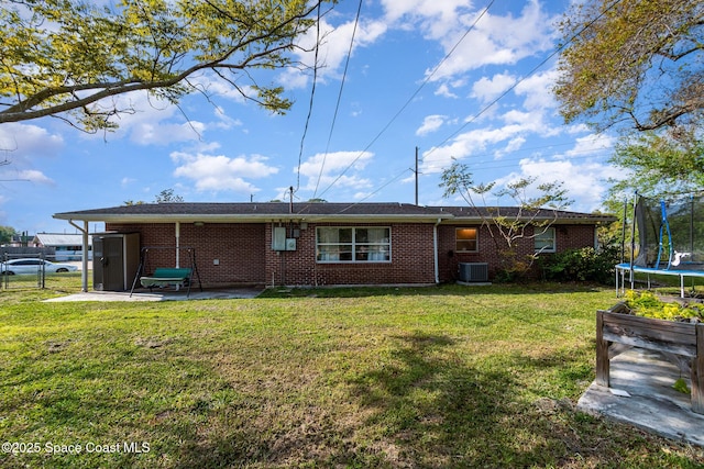 back of property with a yard, a patio, a trampoline, and a gate