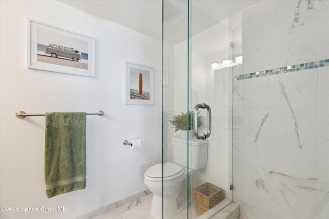 full bathroom featuring toilet, marble finish floor, and a stall shower