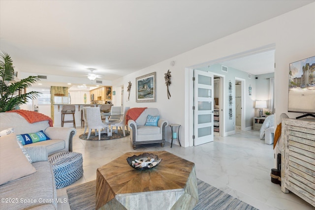 living room featuring visible vents, baseboards, marble finish floor, and ceiling fan