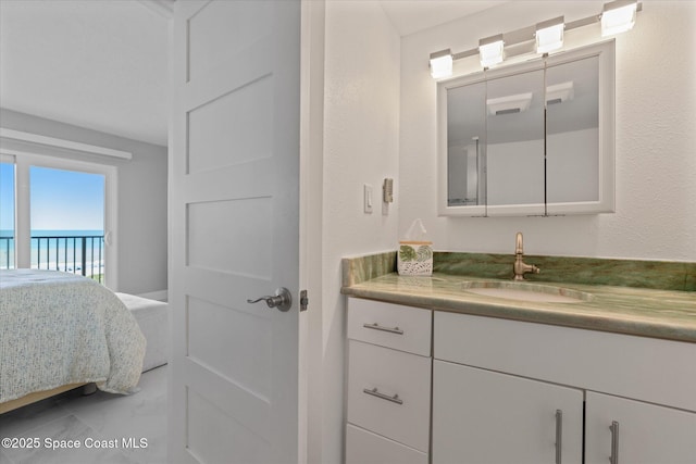 ensuite bathroom featuring vanity, a textured wall, marble finish floor, and connected bathroom