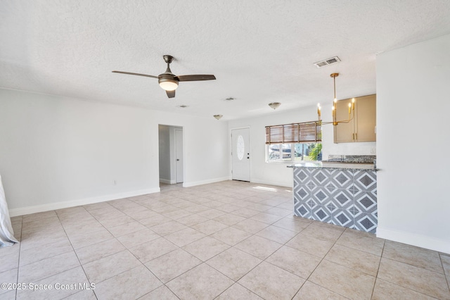 unfurnished living room featuring visible vents, baseboards, ceiling fan, light tile patterned floors, and a textured ceiling