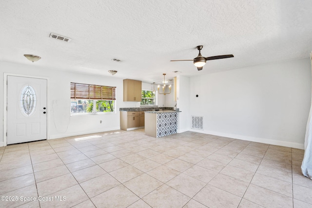 unfurnished living room with light tile patterned floors, visible vents, and ceiling fan with notable chandelier