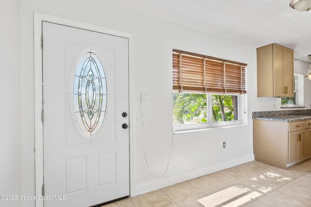 entryway with light tile patterned floors and baseboards