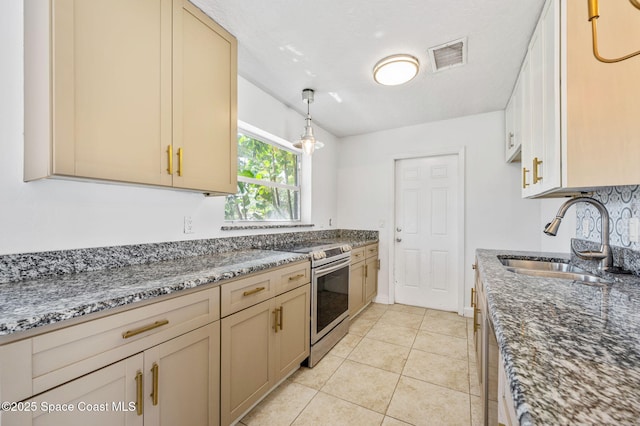 kitchen featuring dark stone countertops, light tile patterned floors, visible vents, stainless steel electric range, and a sink