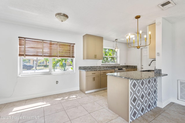 kitchen featuring visible vents, a sink, dark stone countertops, an inviting chandelier, and a peninsula