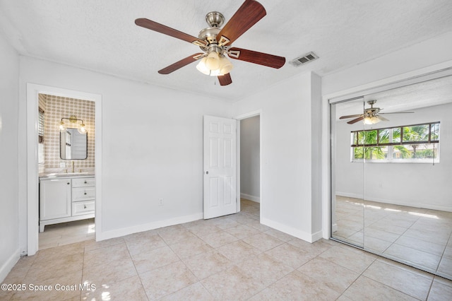 unfurnished bedroom featuring visible vents, baseboards, light tile patterned floors, a closet, and a textured ceiling