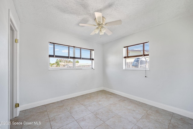 spare room with a textured ceiling, a healthy amount of sunlight, baseboards, and ceiling fan