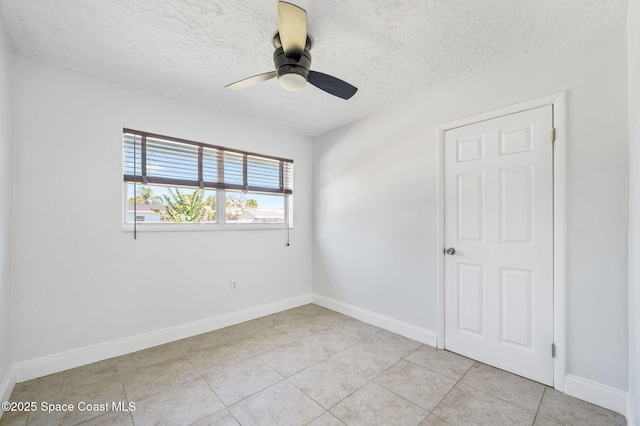 unfurnished room with light tile patterned floors, baseboards, a textured ceiling, and a ceiling fan