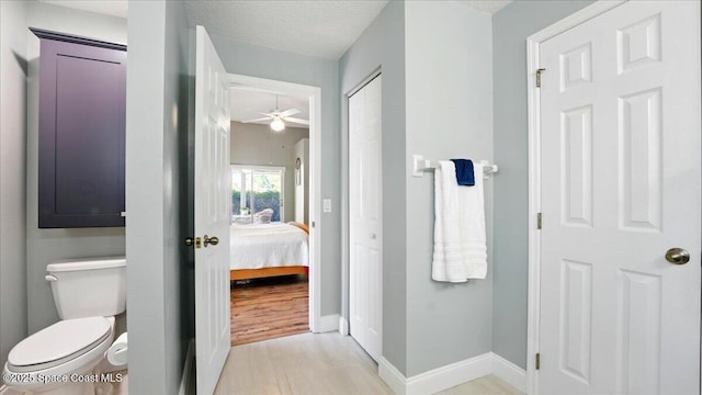 ensuite bathroom with baseboards, ceiling fan, ensuite bathroom, a textured ceiling, and toilet