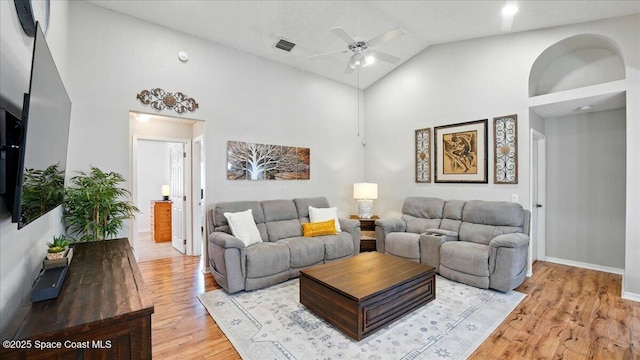 living area featuring visible vents, high vaulted ceiling, a ceiling fan, light wood-style floors, and baseboards