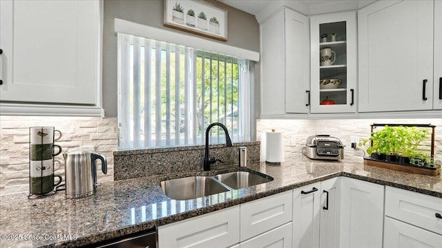 kitchen featuring a sink, decorative backsplash, glass insert cabinets, and white cabinetry