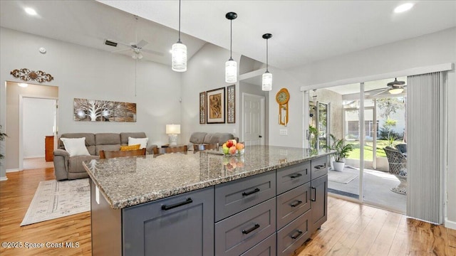 kitchen featuring light wood-style flooring, light stone counters, and ceiling fan