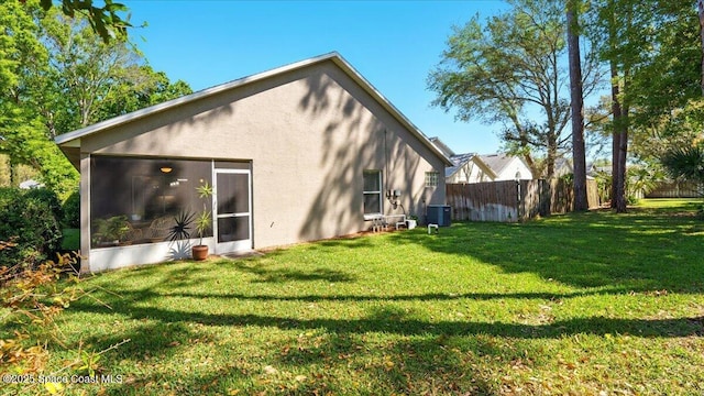 back of property with cooling unit, fence, a yard, a sunroom, and stucco siding